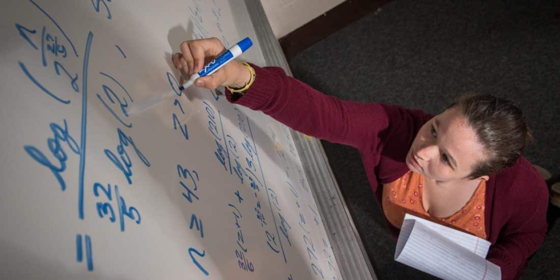 Randolph-Macon faculty member writing mathematics equations on dry erase board.